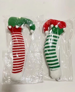Detail of plush Christmas elf legs ornaments in red and green stripes with festive pom-poms