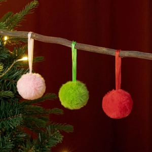 Detailansicht von rosa, grünen und roten Plüsch-Weihnachtskugeln an Zweigen hängend