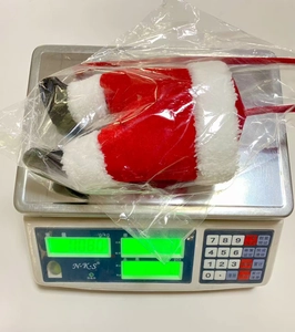 Detailed view of plush Christmas tree ornament legs showing net weight on a digital scale