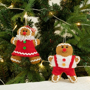 Charmante pluche peperkoekman ornamenten hangend aan een kerstboom met warme lichtjes