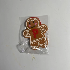 Close-up of a gingerbread man ornament with embroidered letter P and red hanging string