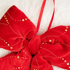 Dettaglio del fiocco natalizio in velluto rosso con glitter dorati e nastro