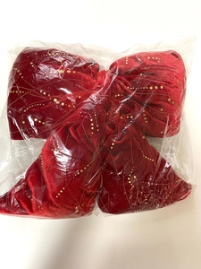Dettaglio di fiocco natalizio in velluto rosso con glitter dorati in pacchetto protettivo