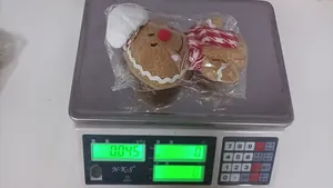 Gingerbread man plush toy with chef hat and scarf on a scale weighing 0.045kg