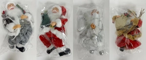 Detailansicht von vier verschiedenen 30 cm Weihnachtsmann-Puppen in festlichen Kostümen