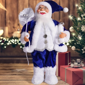 Detailed blue velvet Santa Claus figurine with gift bags next to a decorated Christmas tree