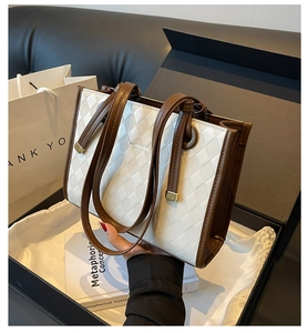 Detail of white quilted tote bag with brown trim inside a luxury gift box packaging