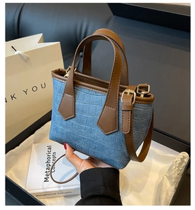 Detail of blue denim and crocodile texture handbag presented in a premium gift box