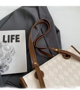 Detail of quilted beige leather tote bag with brown straps and golden logo