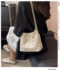 Detail of quilted beige bucket bag with gold chain strap and drawstring closure