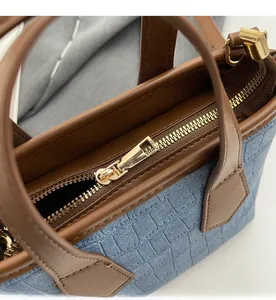 Macro detail of golden metal zipper and brown leather trim on blue crocodile pattern bag