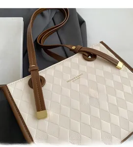 Detail of beige quilted tote bag with brown trim and gold buckle hardware