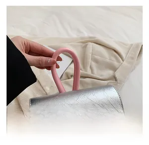 Détail du sac à main argenté texturé avec poignée rose contrastante et aspect métallisé