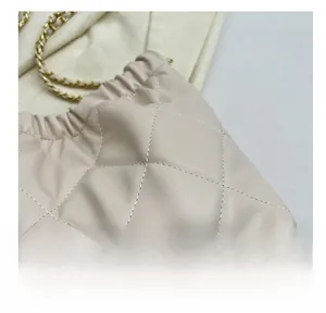 Detail shot of beige quilted leather bag showing fine stitching and gold chain strap