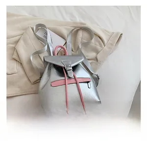 Détail du sac à dos argenté à texture craquelée avec bordure rose et boucle métallique