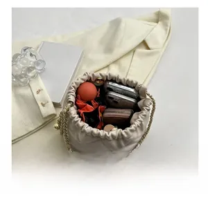 Interior capacity detail of quilted beige bucket bag with gold chain and personal items