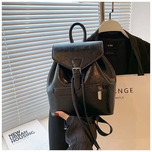 Détail d'un sac à dos en cuir ciré noir brillant avec rabat à boucle et texture lisse
