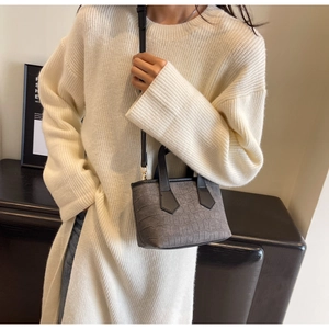 Detail of grey crocodile pattern bucket bag with black handle and shoulder strap