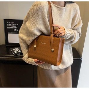 Detail of vintage brown tote bag featuring quilted texture and fashion leather logo