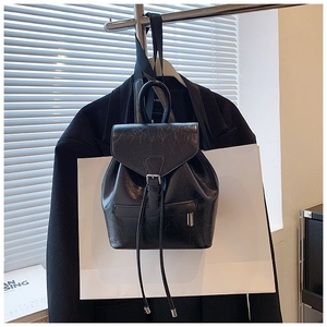 Détail d'un mini sac à dos noir brillant avec texture craquelée et cordon de serrage