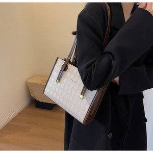 Detail of quilted leather tote bag with brown contrast trim and slim shoulder straps