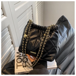 Detail of black quilted chain bag featuring gold drawstring hardware and leather strap
