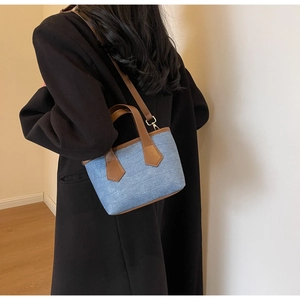 Detail of light blue croc-embossed mini bucket bag with brown leather shoulder strap