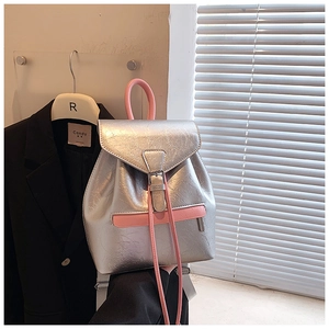 Détail d'un sac à dos argenté froissé avec des bretelles roses et boucles