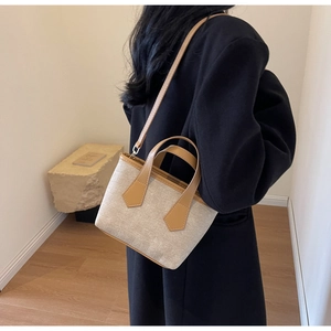 Detail of cross-woven mini tote bag with tan leather shoulder strap on model