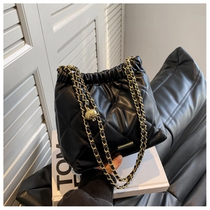 Detail of black quilted leather bucket bag with gold chain strap and drawstring closure