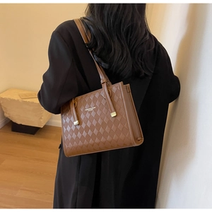 Detail of brown quilted faux leather tote bag with golden metal hardware and long straps