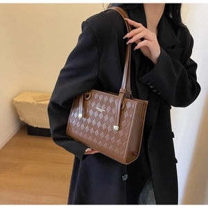 Brown quilted leather tote bag with gold hardware worn by model in casual scene