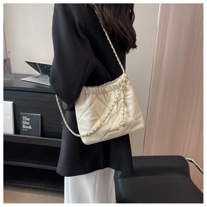 Detail of a creamy quilted chain bucket bag showing soft rhombus texture and gold straps