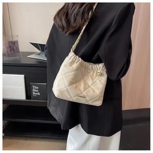 Close-up of beige quilted leather bucket bag with gold chain strap and metal detail