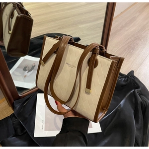 Detail of quilted leather tote bag with brown contrast trim and fashion logo text