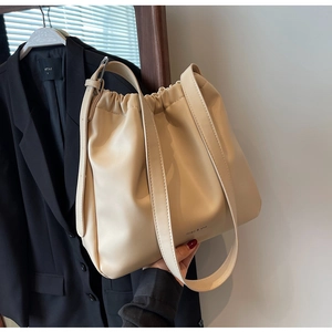 Detailansicht der cremefarbenen Beuteltasche mit Kordelzug und dezentem Logo