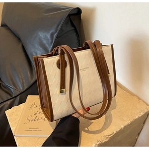 Detail of quilted texture on beige and brown large capacity tote bag with long handles