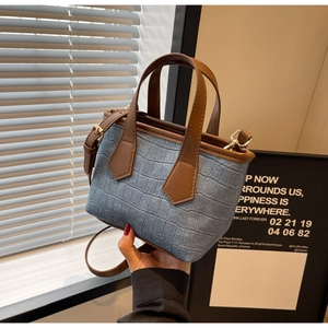 Detail of blue crocodile pattern handbag with brown leather straps and gold metal hardware