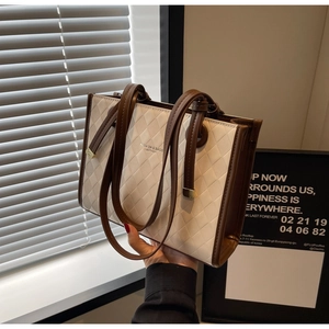 Detail of quilted leather tote bag featuring brown handles and fashion lettering