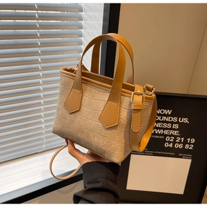 Detailed view of beige crocodile pattern bucket bag with brown handles and gold hardware
