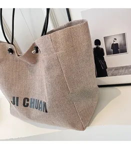 Close-up of large canvas tote bag showing side view, coarse texture, and black handles