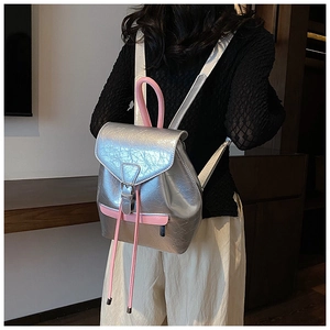 Détail d'un sac à dos argenté texturé avec poignées roses porté par un mannequin