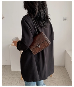 Sac bandoulière vintage en cuir marron foncé porté avec un blazer noir et un jean