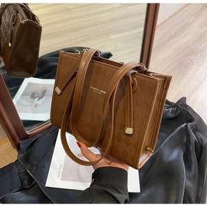 Close-up of brown quilted tote bag with gold lettering and stylish leather texture