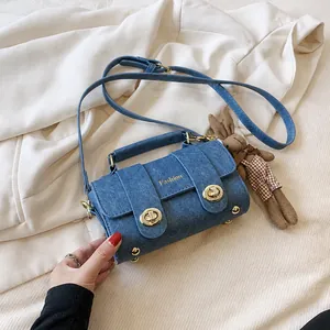 Detail view of blue denim handbag with gold twist locks and cute rabbit charm