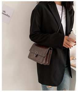 Détail du sac bandoulière marron foncé avec plis en accordéon et texture rétro élégante