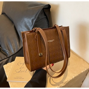 Macro detail of brown quilted leather texture and logo on the stylish tote bag