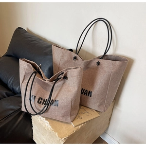 Detail view of woven canvas tote bags in two sizes with black rope handles on art book