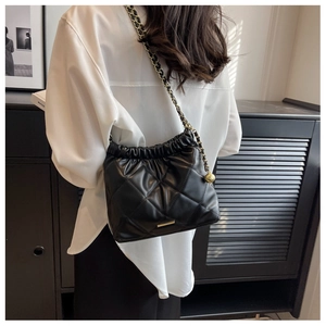 Close-up of quilted black leather bucket bag with gold chain strap and metal ball