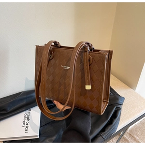 Detail of brown quilted tote bag featuring embossed texture and top handles for women
